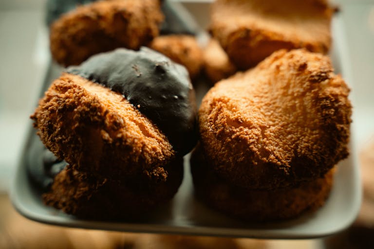 A tempting display of coconut macaroons, some dipped in chocolate, on a plate.