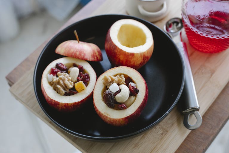 Delicious stuffed apples filled with nuts and berries on a black plate, perfect for a fall treat.